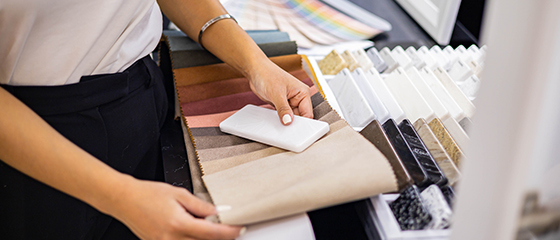 a person matching a countertop sample with fabric samples with a Pantone book in the background